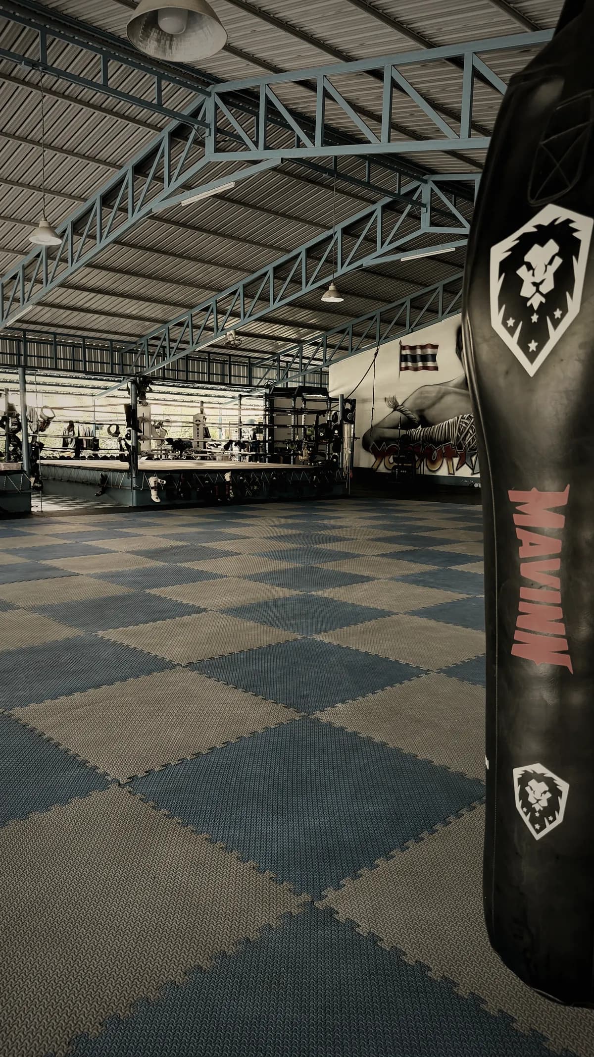 Sac de frappe au premier plan et ring en arrière-plan dans la salle Yodyut Muay Thai à Koh Samui